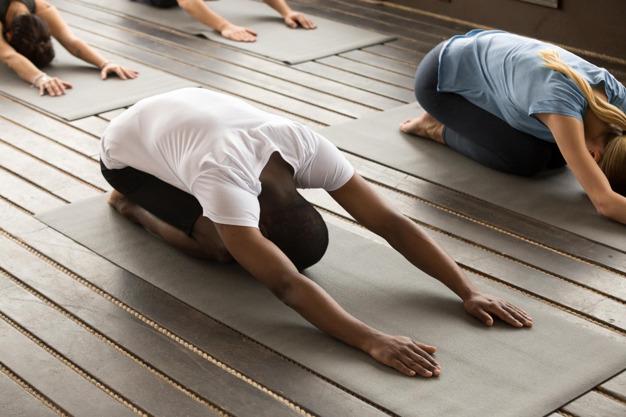 En gruppe mennesker som praktiserer yoga på fargerike matter i en rolig utendørs setting.